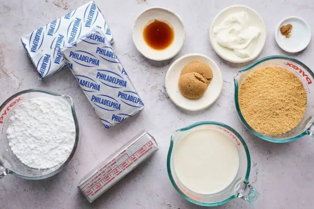 Key Ingredients For Philadelphia No-Bake Cheesecake An overhead view of the simple, wholesome ingredients needed for a Philadelphia no-bake cheesecake, including classic foil-wrapped cream cheese, graham cracker crumbs, butter, and sugar, resting on a bright kitchen counter.